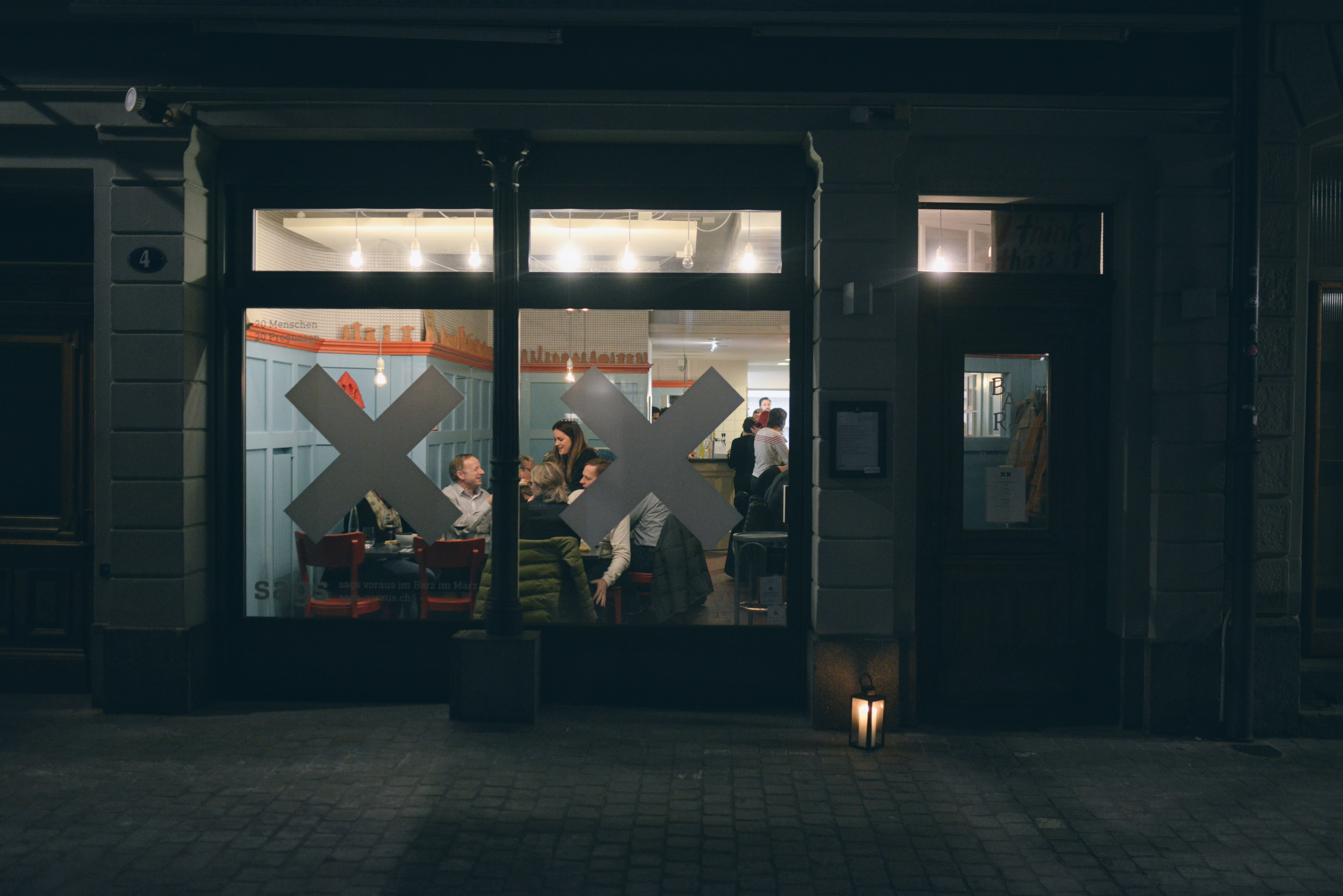 Restaurantfassade mit Glasfront und aufgeklebten XX-Symbolen als Sichtmarkierung.