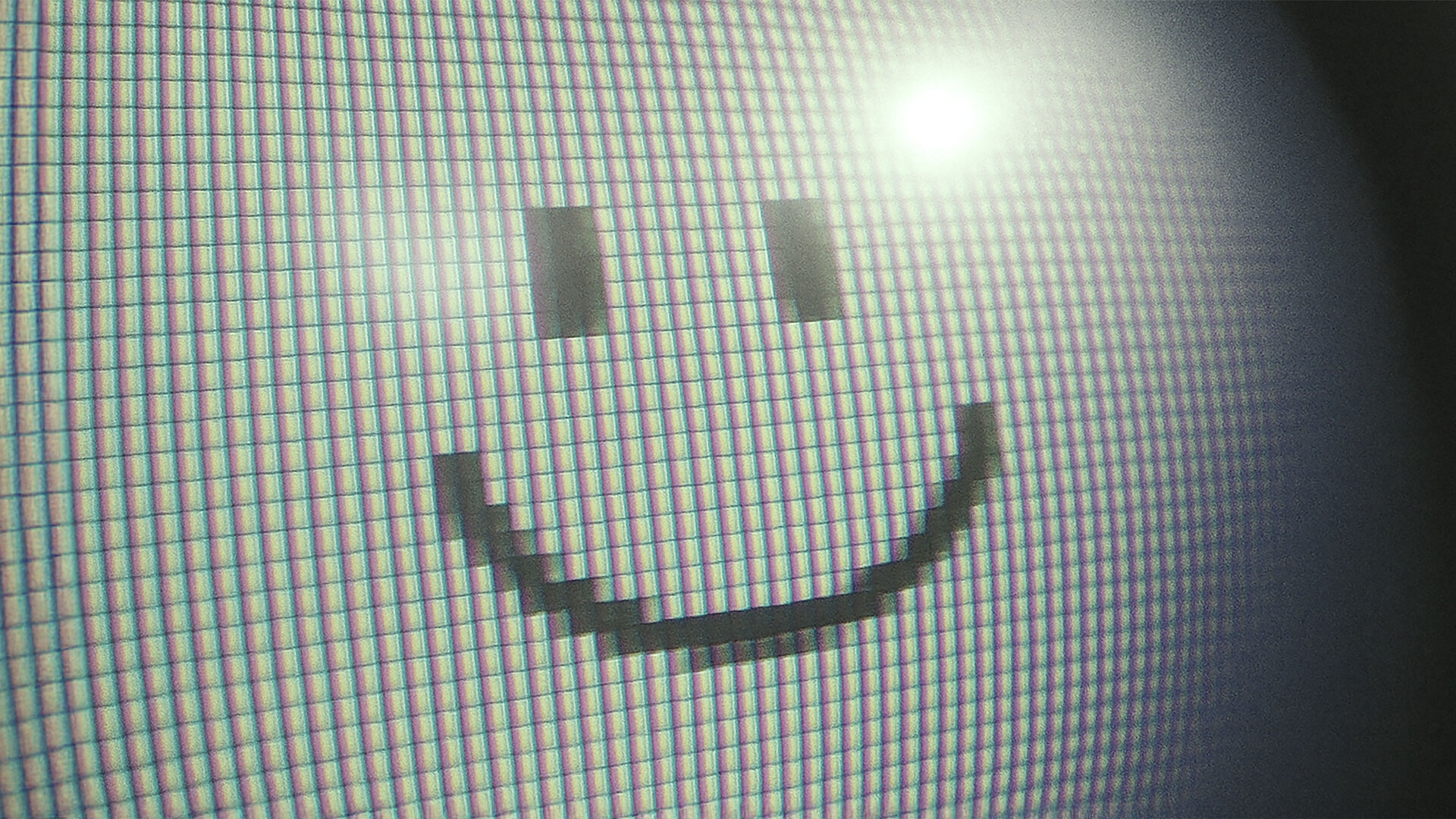 Pixeliger Smiley auf einem Bildschirm mit sichtbarer Rasterstruktur in Nahaufnahme.